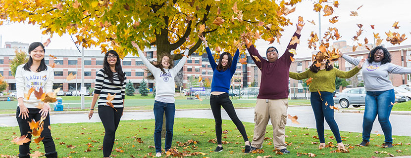 students on campus throwing leaves