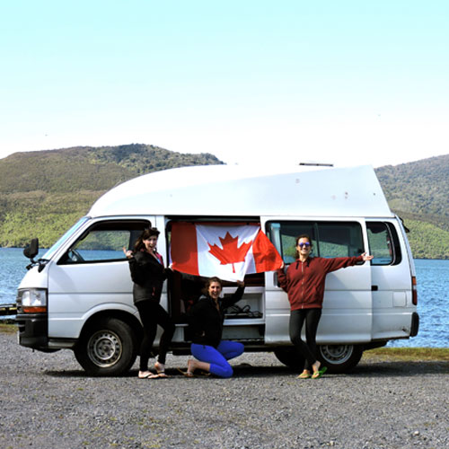 Students holding up Canada flag in front of van