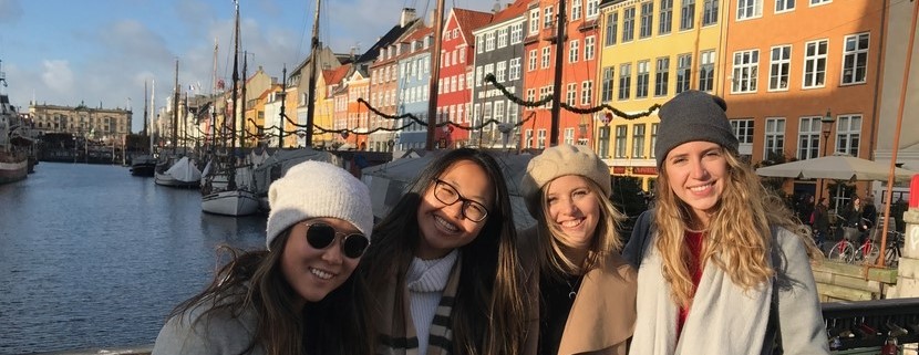 Amy Dang, Laurier student, with 3 friends in front of a picturesque canal with bright coloured buildings in the background.