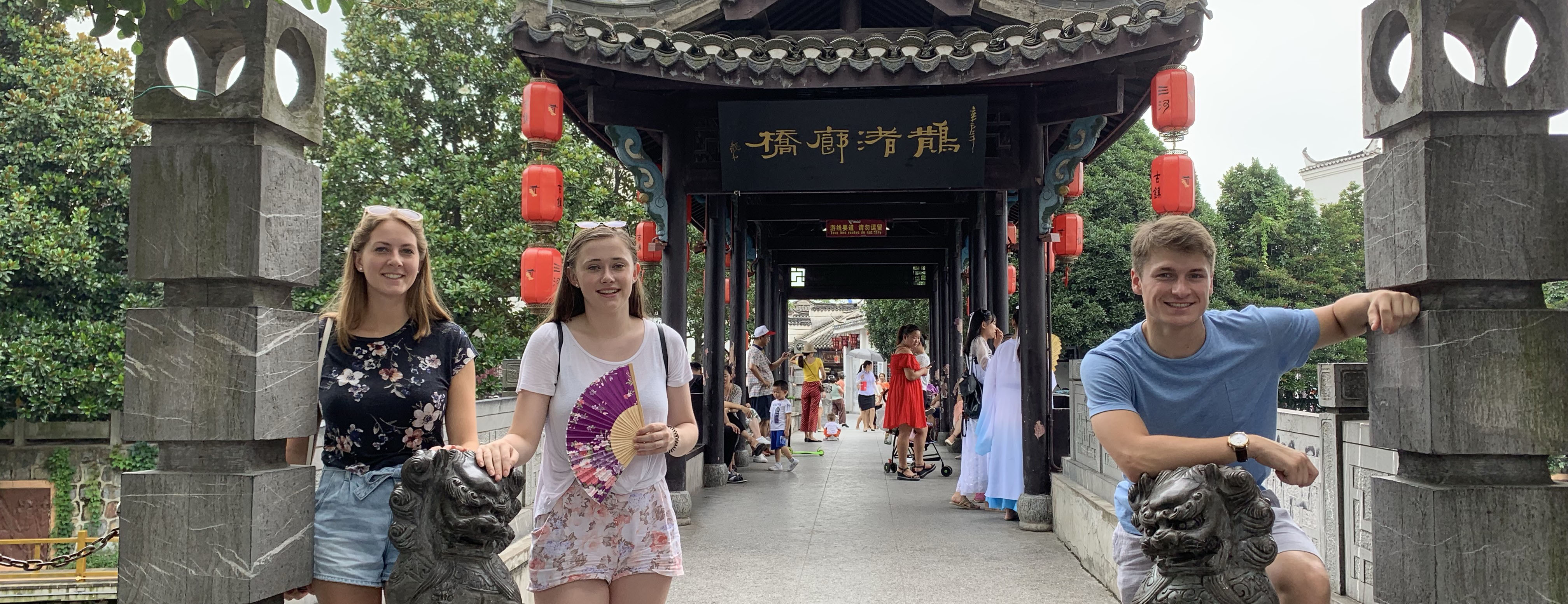 three students sitting in front of a Chinese temple