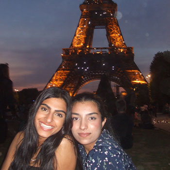 Sehar and her friend, Hana in front of the Eiffel Tower at night.