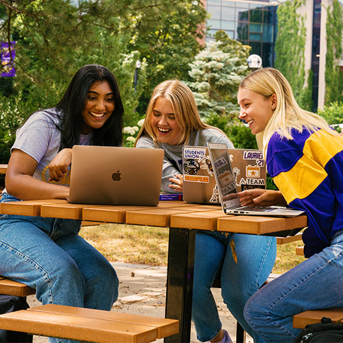 Three students looking at their laptops