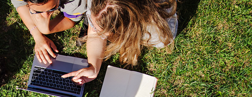 Students laying on lawn and studying