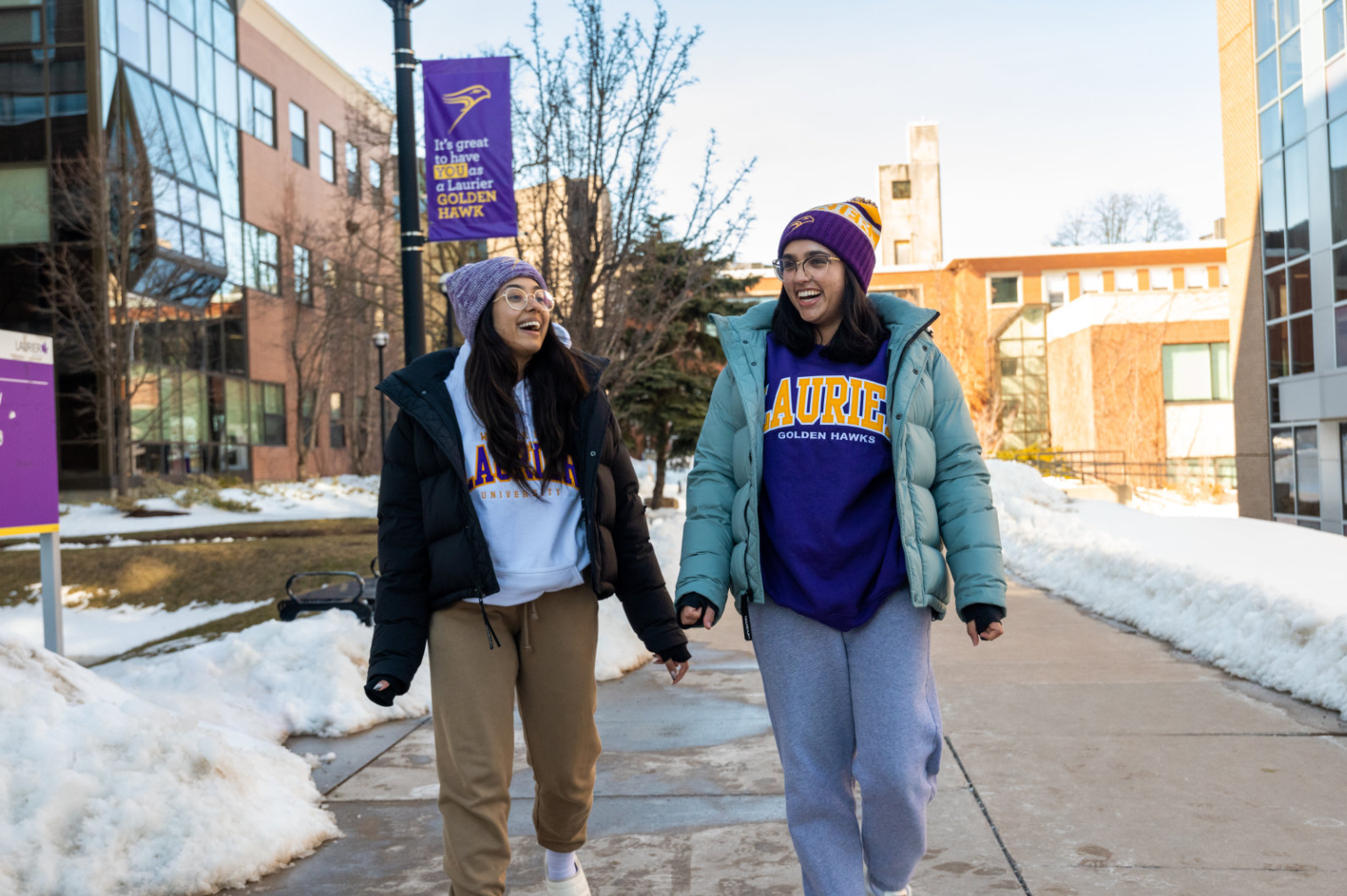 two female students walking on a winter day dressed in Laurier gear