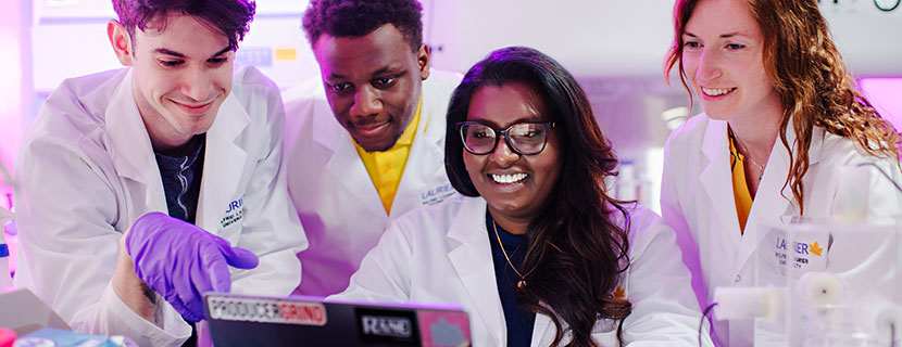 Nirosha Murugan and students looking at a laptop together