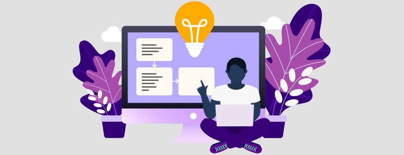 student sitting with laptop in front of large desktop