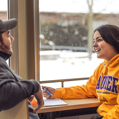 Two students chatting with each other in the concourse.