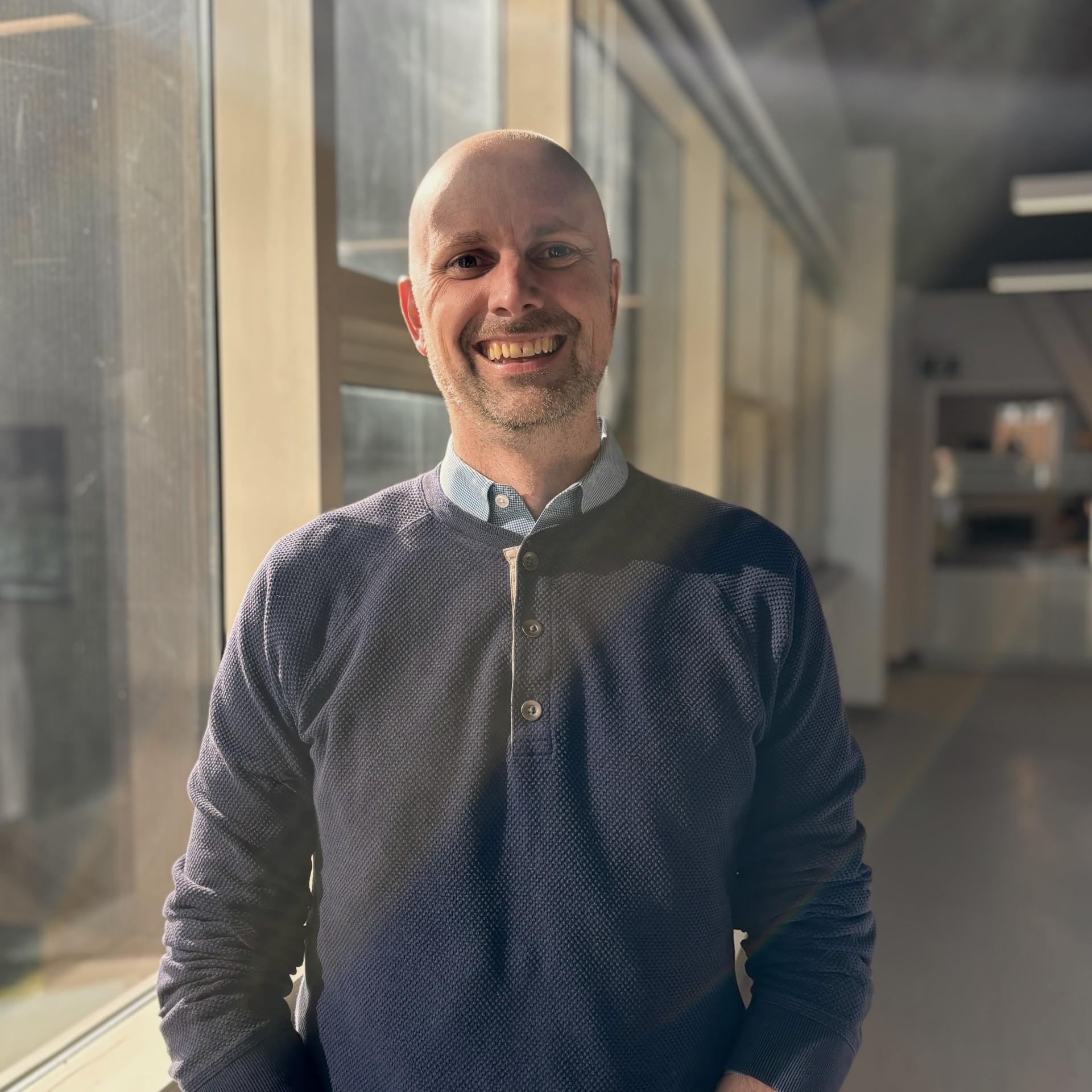 bald man smiling wearing a grey sweater