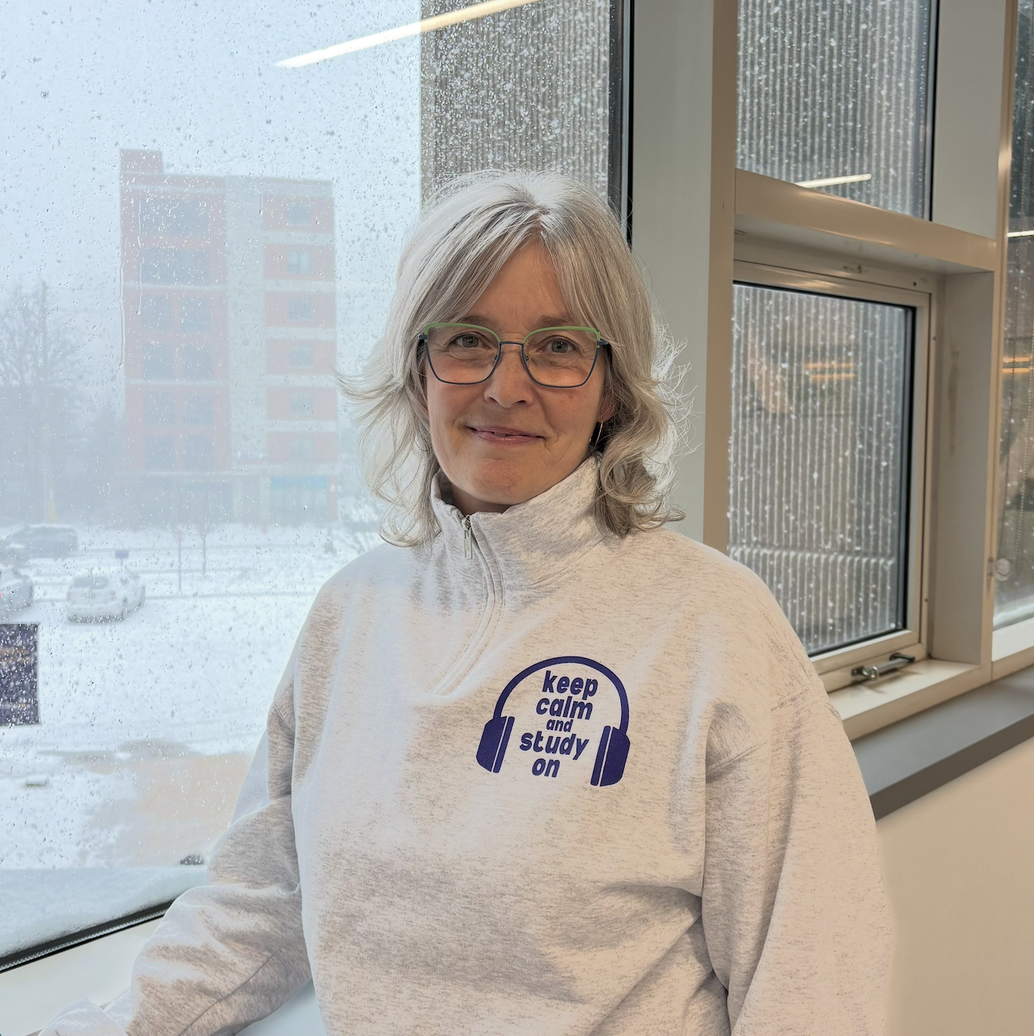 women with short grey hair smiling with green glasses