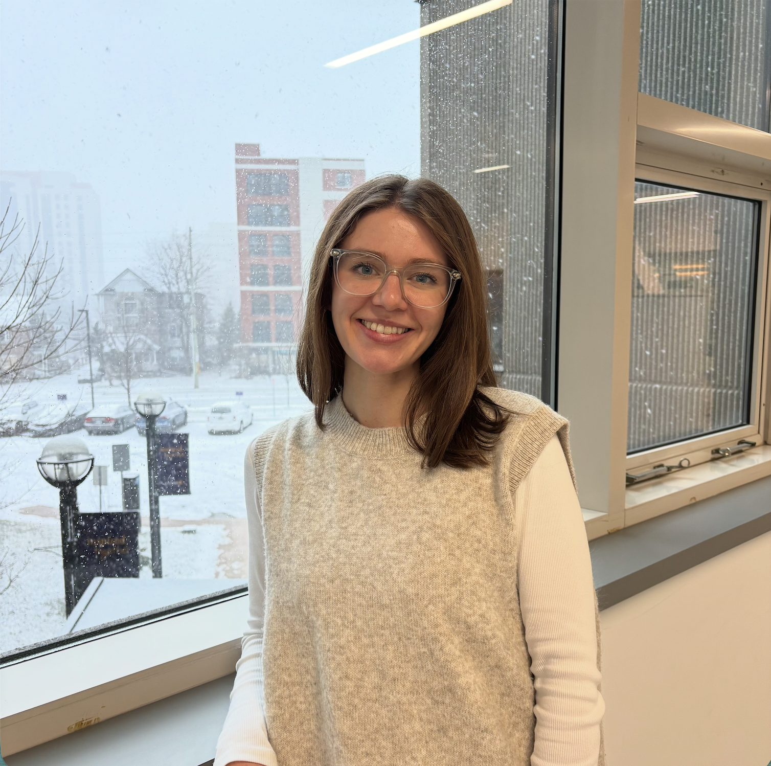Women with brown hair smiling wearing a cream knit sweater