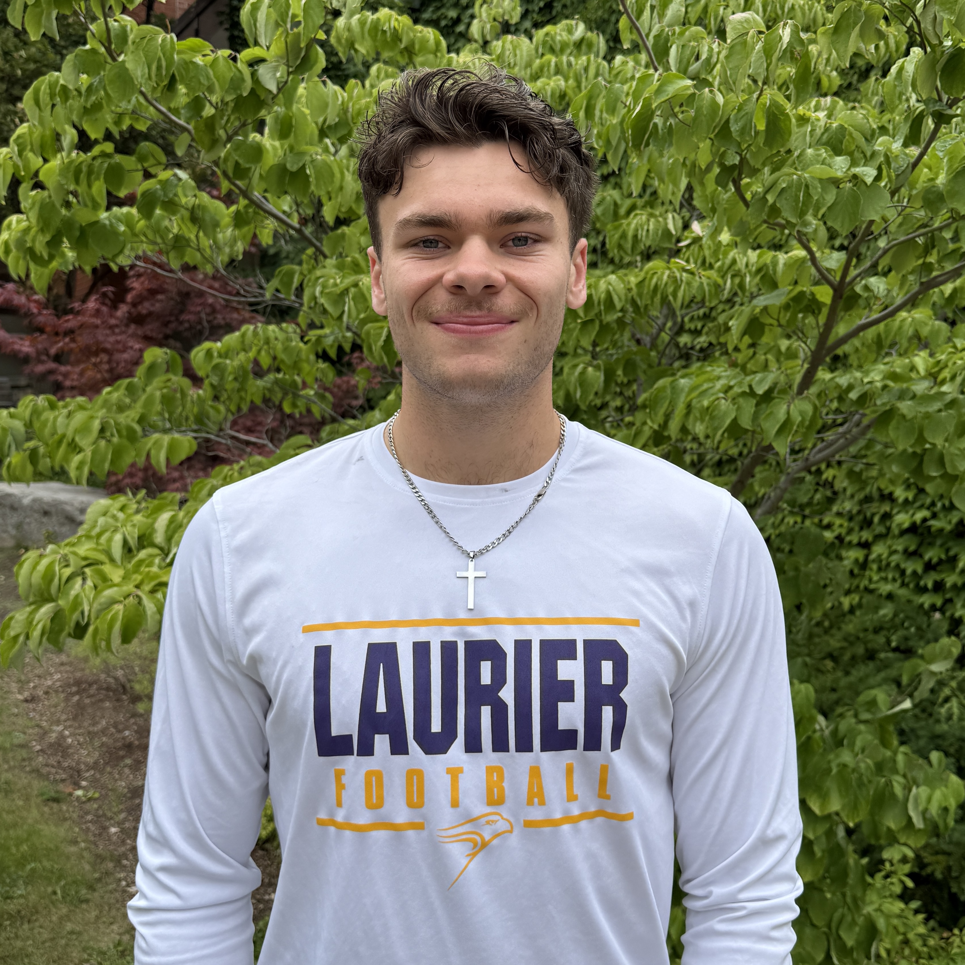 white man with brown hair smiling in a Laurier shirt