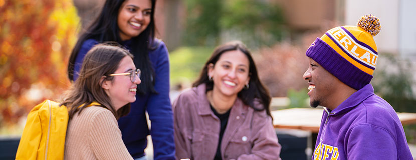 three female students and a male student chatting and laughing