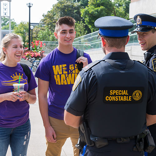 Two special constables in conversation with two students