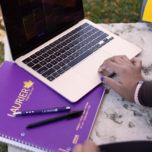 Laurier-branded notebook next to laptop.