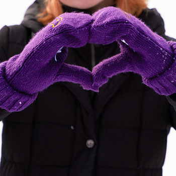 Student wearing winter gloves doing the heart symbol with hands