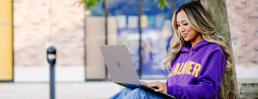 Student sitting outside, typing on laptop