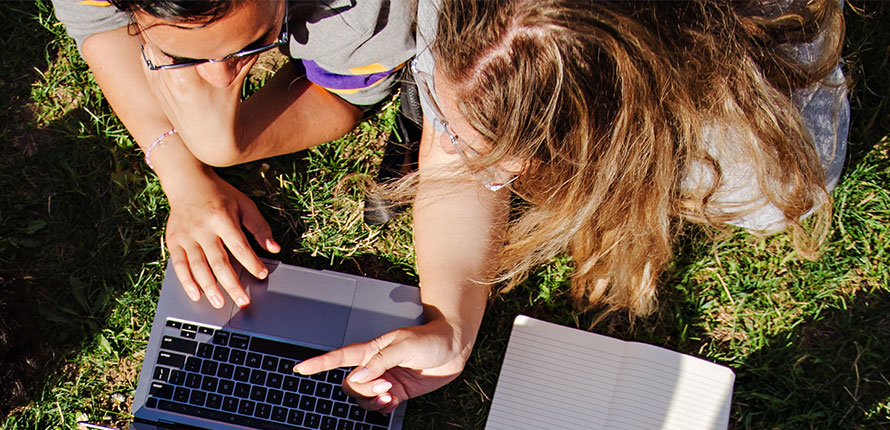 Two students working at laptop