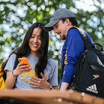 Female and male student looking at mobile device that female student is holding.