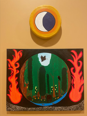 A drum painted with the image of a crescent moon hangs above a rectangle canvas depicting a forest framed by a circle with fire on either side.