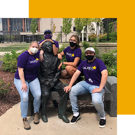 students posing with wilf statue