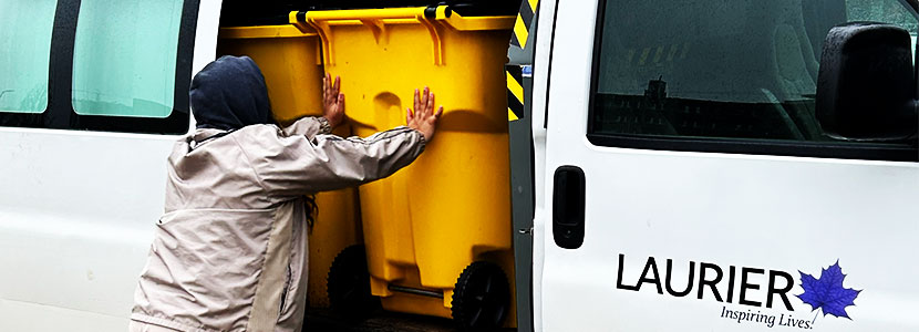 Man loading yellow bins into van.