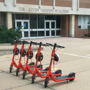 Neuron scooters lined up in front of Dr. Alvin Woods Building