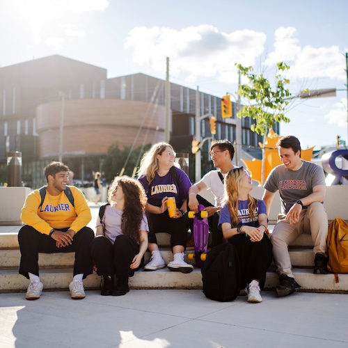Students sitting on steps talking and laughin