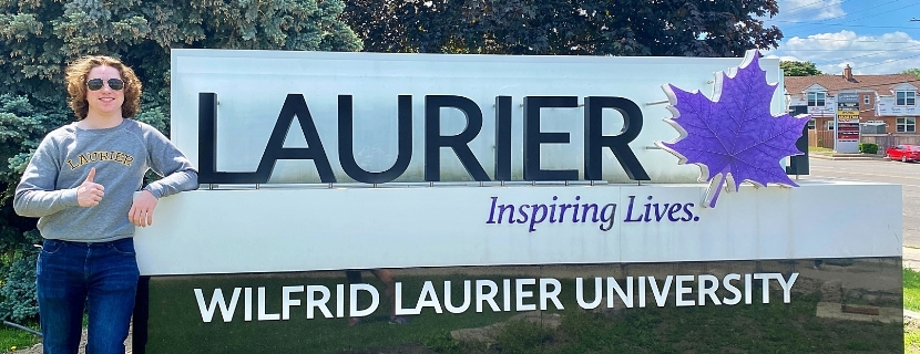 student in front of Laurier sign